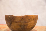 Close-up of primitive hand-carved African wooden bowl, revealing etched lines and aged character.