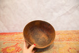 Hand holds vintage African bowl, showing its dark, primitive wood interior and aged character.
