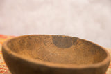 A dark repair and visible crack on the aged, textured rim of a wooden bowl.