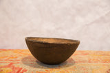 Primitive hand-carved wooden bowl with dark, aged patina and textural imperfections.