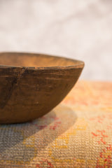 Close-up of vintage African bowl rim with crack, chips, and aged wood texture.