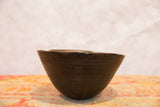 Aged dark wood African bowl with hand-carved lines and natural imperfections on its rim.