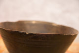 Aged dark wood rim of a vintage African bowl with visible chips and cracks.