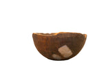 Primitive hand-carved African wooden bowl, dark brown with visible rustic imperfections.