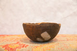 Hand-carved vintage African bowl displaying natural cracks and aged primitive repairs.