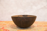 Vintage hand-carved African wooden bowl with horizontal lines and mended crack.