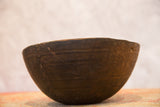 Wooden African bowl showing hand-carved lines and a distinct stitched repair.