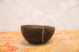 Detail of the vintage wooden African bowl showing a prominent crack and aged texture.