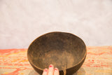 Hand-carved dark wood interior of a vintage African bowl, showing a distinct crack.