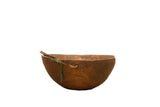 Vintage hand-carved primitive African wooden bowl with green fiber and rustic texture.