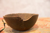 Vintage wooden African bowl with visible crack and hand-stitched repair detail.