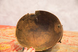 Interior of vintage African wooden bowl showing prominent crack and brass detail.