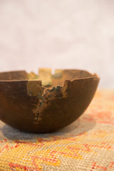 Vintage African wooden bowl with a crack, green wire repairs, and brass edge.