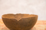 Uneven rim and aged, primitive texture of a hand-carved vintage African wooden bowl.