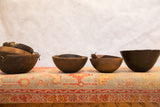 Four unique vintage hand-carved wooden African bowls with visible imperfections.