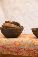 Stacked primitive dark wood African bowls with aged cracks and metal repairs.
