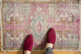 Distressed Oushak rug's oblong medallion with muted aubergine, sea foam green, ivory tones.
