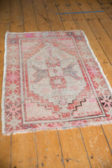 Distressed Oushak rug close-up, showcasing faded brick red, blush pink, and worn texture.