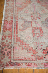 Oushak rug's worn texture, showcasing brick red, blush, and pink geometric border design.