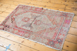 Distressed vintage Oushak rug corner showing secured fringe and faded brick red, pink, and ivory borders.