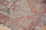 Distressed Oushak rug's worn pile texture with brick red, pink, and beige patterns.
