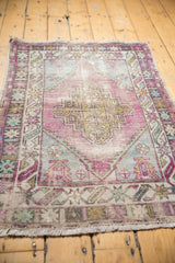 Distressed hand knotted Oushak rug showing geometric stepped medallion with pastel aubergine and sea foam green tones.