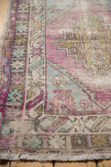 Distressed Oushak rug border and fringe, showing worn geometric patterns in aubergine, seafoam.