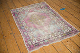 Distressed Oushak rug corner with pinwheel plants, aubergine, sea foam, and worn pile.