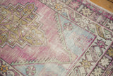 Close-up of distressed Oushak rug showing faded aubergine, blue patterns, and visible wear.