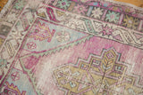 Distressed Oushak rug section with textured geometric patterns in pink, sea foam, and ivory.