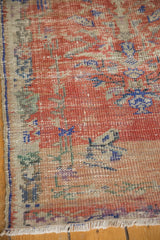Distressed vintage Oushak rug texture revealing worn pile, visible foundation, red, and ivory.