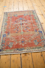 Distressed brick red Oushak rug pile with ivory, royal blue accents, and secured edge.