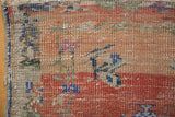 Distressed Oushak rug corner, highlighting worn pile, foundation, and original selvage.