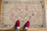 Vintage distressed Oushak rug showing worn pile, central diamond medallion, and soft pale mauve and ivory tones.