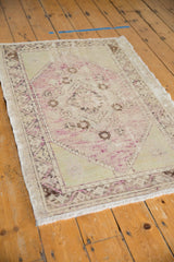 Distressed Oushak rug detail with worn pile, pale mauve, and ivory diamond motif.