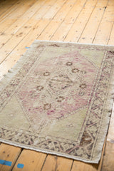 Distressed vintage Turkish Oushak rug corner displaying faded pale mauve, ivory, charcoal patterns.