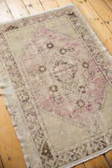 Distressed Oushak rug corner, faded mauve, ivory, brown tones, and visible worn foundation.