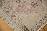 Corner of distressed vintage Oushak rug, highlighting worn antique ivory pile and patterned border.
