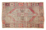 Distressed vintage Oushak rug, oversized diamond medallion, faded texture with soft pink, green, and beige.
