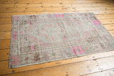Distressed texture with bubble gum pink and mint green motifs on a vintage Oushak rug corner.