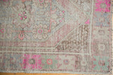 Vintage Distressed Oushak rug corner with worn pile, pink, silver, mint green, and intact fringe.