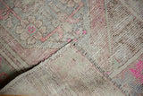 View of the distressed Oushak rug, highlighting worn pile, bright pink, and woven foundation.