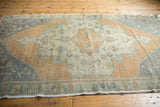 Distressed Oushak rug with scalloped medallion, sandalwood, antique ivory, seafoam tones.