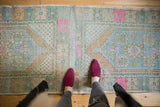 Distressed Oushak rug runner's plain-woven center, showcasing faded blues, greens, and pink.