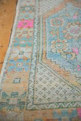 Distressed Oushak runner with worn pile, faint foundation, and bright pink floral motifs.