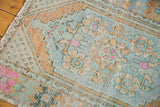 Distressed Oushak rug pile detail, with worn geometric motifs in sea foam, pale orange, and pink.