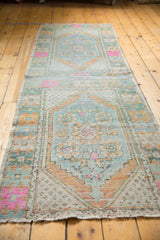Oushak runner's distressed texture reveals blue, pale orange, and vivid pink floral motifs.
