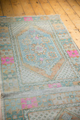 Distressed vintage Oushak runner's central plain-woven seam, highlighting pink, orange, and blue motifs.