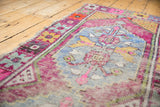 Distressed vintage Oushak runner texture with playful pink, blue, yellow floral motifs.