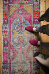 Distressed vintage Oushak runner with vivid pink, blue, yellow diamond medallion and floral border.